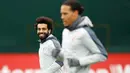 Gelandang Liverpool Mohamed Salah (kiri) tersenyum saat sesi latihan jelang menghadapi Bayern Munchen dalam leg kedua babak 16 besar Liga Champions di Melwood, Liverpool, Inggris, Selasa (12/3). (Martin Rickett/PA via AP)