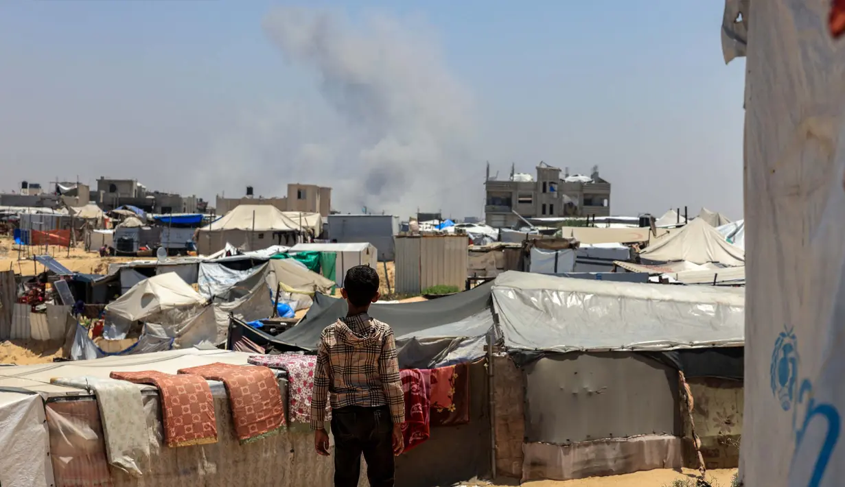 Seorang anak Palestina melihat kepulan asap mengepul dari kejauhan selama pemboman Israel di Rafah, Jalur Gaza Selatan pada 11 Juni 2025. (Foto oleh AFP)