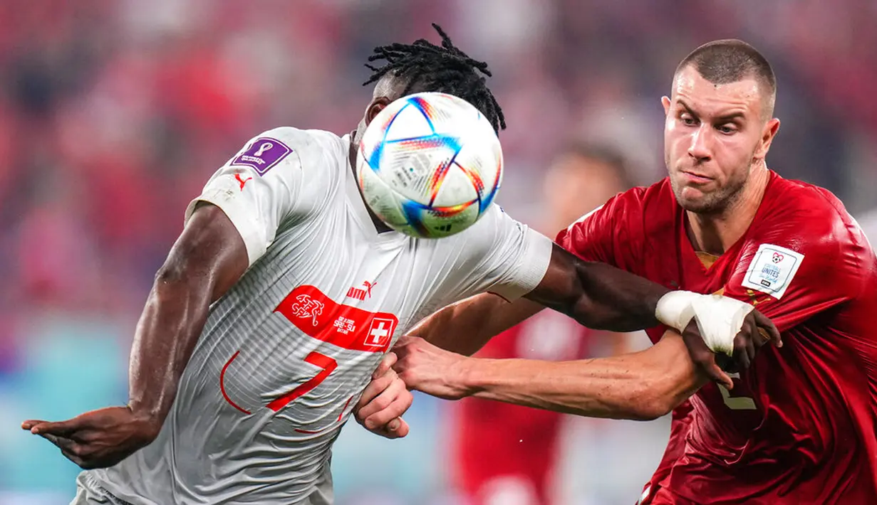 Pemain Swiss Breel Embolo (kiri) berebut bola dengan pemain Serbia Strahinja Pavlovic pada pertandingan sepak bola Grup G Piala Dunia 2022 di Stadion 974, Doha, Qatar, 2 Desember 2022. Swiss melaju ke babak 16 besar Piala Dunia 2022 setelah mengalahkan Serbia dengan skor 3-2. (AP Photo/Petr David Josek)