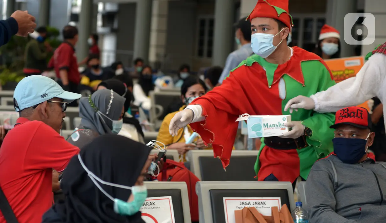 Petugas KAI yang mengenakan kostum Natal membagikan masker kepada calon penumpang di Stasiun Senen, Jakarta, Jumat (25/12/2020). Pembagian ini dilakukan untuk mengganti masker yang sudah dipakai calon penumpang selama perjalanan. (merdeka.com/Imam Buhori)