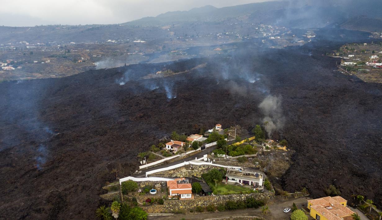 Lava dari letusan gunung Cumbre Vieja mengalir menghancurkan rumah-rumah di pulau La Palma di Canaries, Spanyol, Selasa (21/9/2021). Diketahui gunung berapi ini merupakan salah satu daerah vulkanik paling aktif di Canaries dan pernah mengalami letusan besar pada tahun 1971. (AP/Emilio Morenatti)