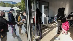 Orang tua mengantre di pusat vaksinasi bersama anak-anak mereka yang akan menerima vaksin covid-19 di ibu kota Siprus, Nicosia, Minggu (2/1/2022). Siprus memulai vaksinasi untuk anak-anak berusia antara 5 hingga 11 tahun, di tengah lonjakan tajam kasus virus corona. (Iakovos Hatzistavrou / AFP
