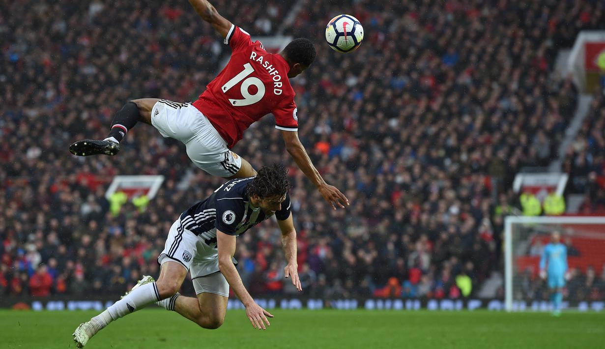 Pemain Manchester United, Marcus Rashford (atas) melakukan duel dengan pemain West Bromwich, Jay Rodriguez pada lanjutan Premier League di Old Trafford, Manchester,(15/4/2018). Manchester United kalah 0-1. (AFP/Paul Ellis)