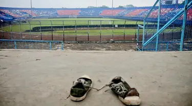 Sepasang sepatu terlihat di tribun Stadion Kanjuruhan setelah tragedi kerusuhan pada pertandingan sepak bola antara Arema Vs Persebaya di Malang, Jawa Timur, Minggu (2/10/2022). Dunia sepak bola Indonesia kembali berduka menyusul terjadinya kerusuhan pascapertandingan Arema vs Persebaya. (AP Photo/Hendra Permana)