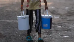 Seorang gadis membawa ember berisi air yang dikumpulkan dari truk tangki air perusahaan kota di lingkungan berpenghasilan rendah di New Delhi pada Kamis (3/6/2021). Kelangkaan air secara tidak proporsional mempengaruhi orang-orang rentan di masyarakat berpenghasilan rendah. (Money SHARMA / AFP)
