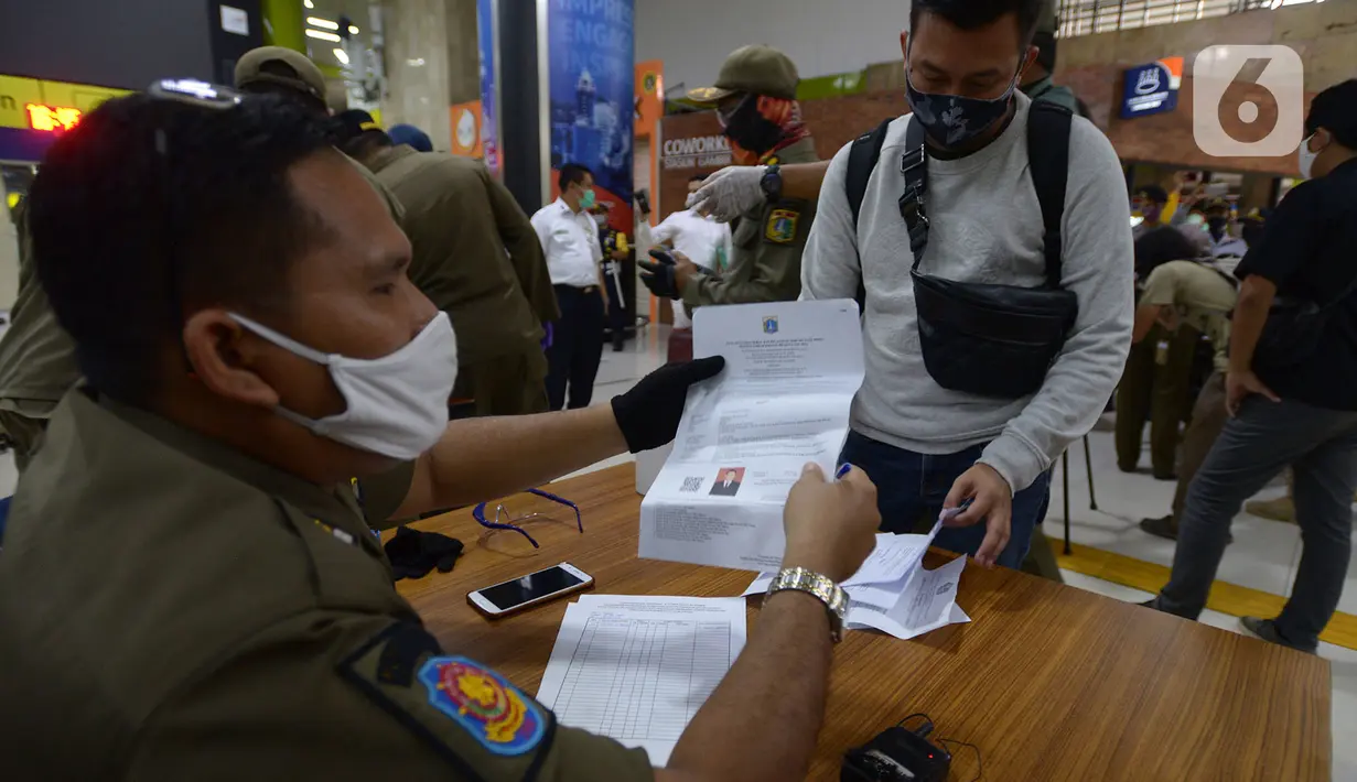 Petugas mengecek SIKM milik penumpang di stasiun Gambir Jakarta, Kamis (28/5/2020). Penumpang yang mudik dari Surabaya mengunakan kereta api luar biasa harus memiliki SIKM sebagai syarat yang dimiliki warga untuk keluar atau masuk ke wilayah Jakarta. (merdeka.com/Imam Buhori)