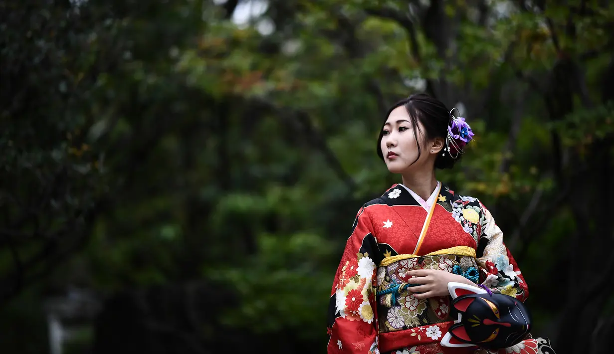 Gambar pada 21 Oktober 2019 menunjukkan seorang perempuan mengenakan pakaian tradisional Jepang, kimono, saat mengunjungi kuil Senso-ji di Tokyo. Sensoji Temple merupakan salah satu kuil tertua di Jepang yang terletak di Asakusa. (Anne-Christine POUJOULAT / AFP)