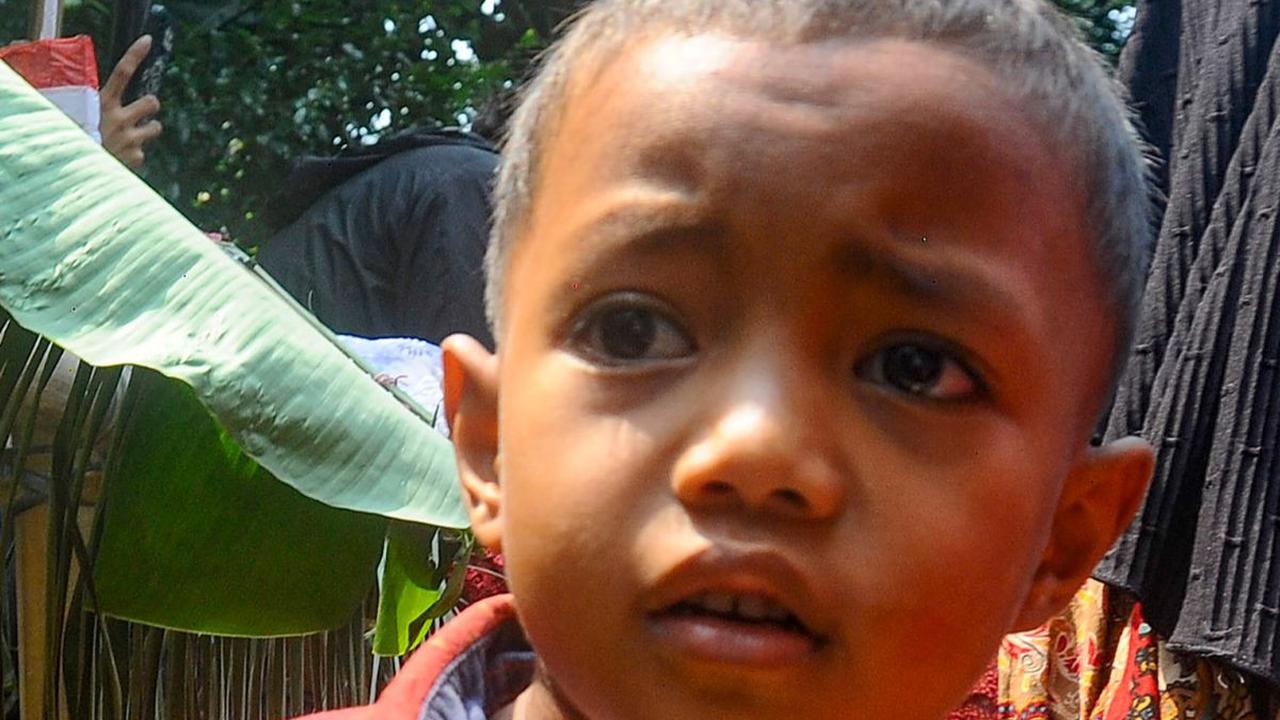 Ekspresi seorang anak yang berhasil mendapatkan beberapa buah setelah ikut rebutan hasil panen.