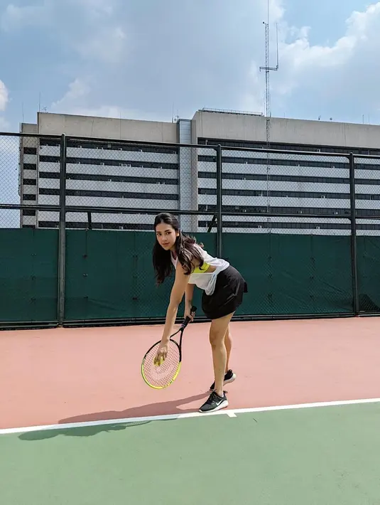 Foto yang diunggah di akun Instagram, Anya Geraldine berpose bak petenis profesional saat melakukan servis. Anya yang sudah memegang raket dan bola berpose sedikit menungging sebelum melakukan servis. Ia tampil dengan baju putih tanpa lengan dan rok hitam super mini. (Instagram/anyageraldine)