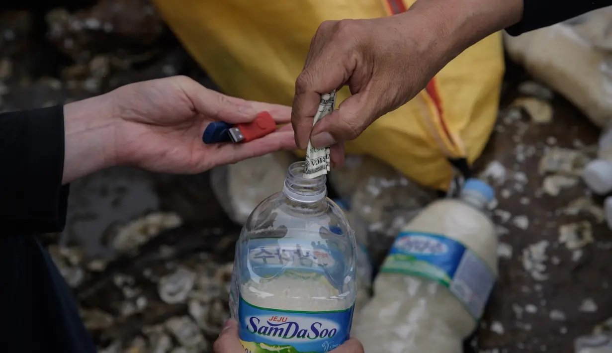 Aktivis pembelot Korea Utara memasukkan beras, uang dan USB ke dalam botol sebelum dilemparkan ke laut dari pulau Ganghwa di barat Seoul, Selasa (1/5). Kegiatan ini telah dilakukan kelompok aktivis pembelot Korut sejak dua tahun terakhir. (AFP/ED JONES)