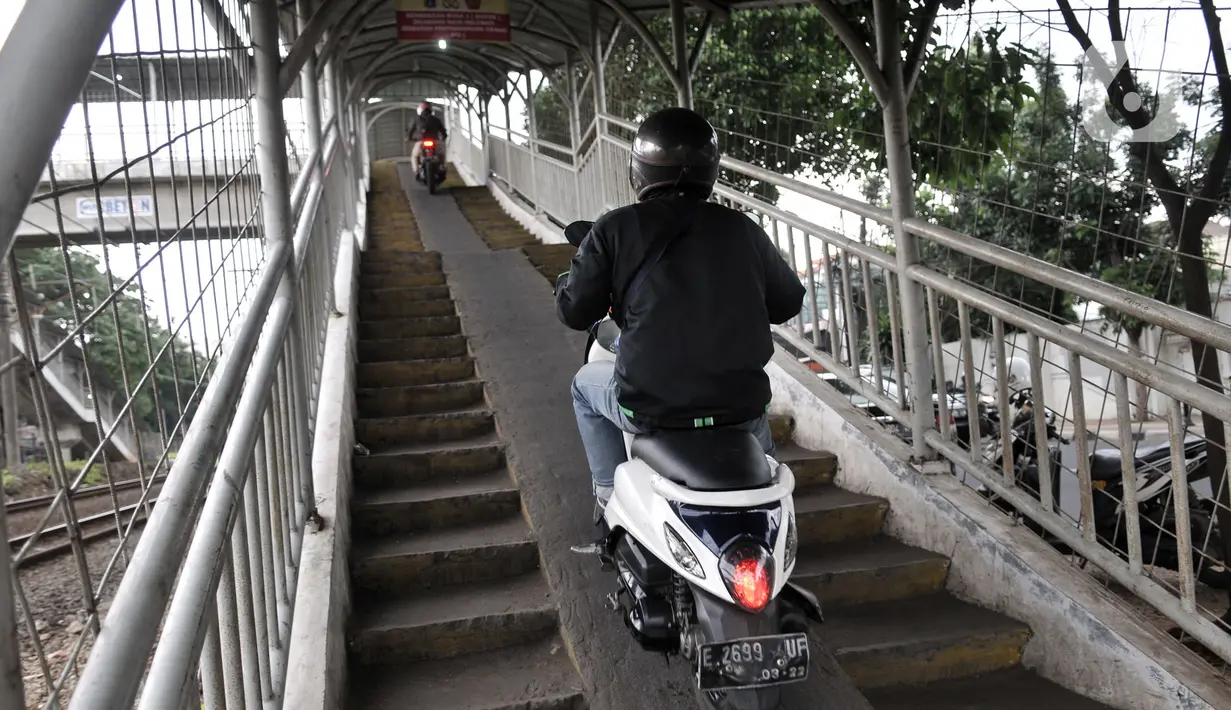 Pengendara sepeda motor melintasi jembatan penyeberangan orang (JPO) Stasiun Pasar Minggu Baru, Jakarta, Selasa (10/3/2020). JPO tersebut kerap disalahgunakan pengendara motor sebagai jalan alternatif untuk mempersingkat jarak tempuh meski telah banyak kecelakaan terjadi. (merdeka.com/Iqbal Nugroho)