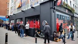 Orang-orang mengantre untuk memasuki toko andalan The Rolling Stones yang baru sebelum hari pertama pembukaannya di London, Rabu (9/9/2020). Toko tersebut akan menjual busana dan merchandise, serta musik, dari band rock The Rolling Stones. (Tolga Akmen / AFP)