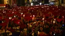 Orang-orang yang bersuka ria mengenakan warna putih dan merah sambil memegang lilin dan sapu tangan saat mereka menyanyikan lagu San Fermin "Pobre de Mi" untuk menutup sembilan hari adu banteng, musik, dan tarian, pada Festival San Fermin di Pamplona, Spanyol, 15 Juli 2022. (AP Photo/Alvaro Barrientos)