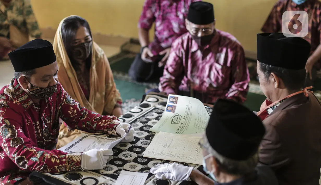 Pasangan pengantin menjalani prosesi akad nikah di KUA Pondok Pinang, Kebayoran Lama, Jakarta, Jumat (17/7/2020). Di masa PSBB transisi, pihak KUA menikahkan 8-10 pasangan per hari dengan mengikuti protokol kesehatan sesuai Surat Edaran Menteri Agama Nomor 15 Tahun 2020. (Liputan6.com/Johan Tallo)