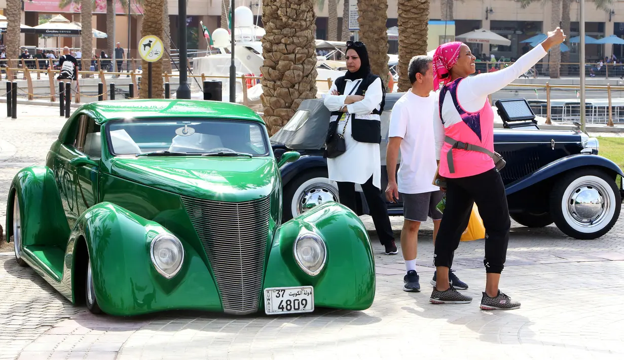 Seorang wanita berswafoto dengan mobil Ford kelas A 1937 dalam pameran mobil klasik di Marina Crescent, Kuwait City, Kuwait, 29 Oktober 2021. (YASSER AL-ZAYYAT/AFP)