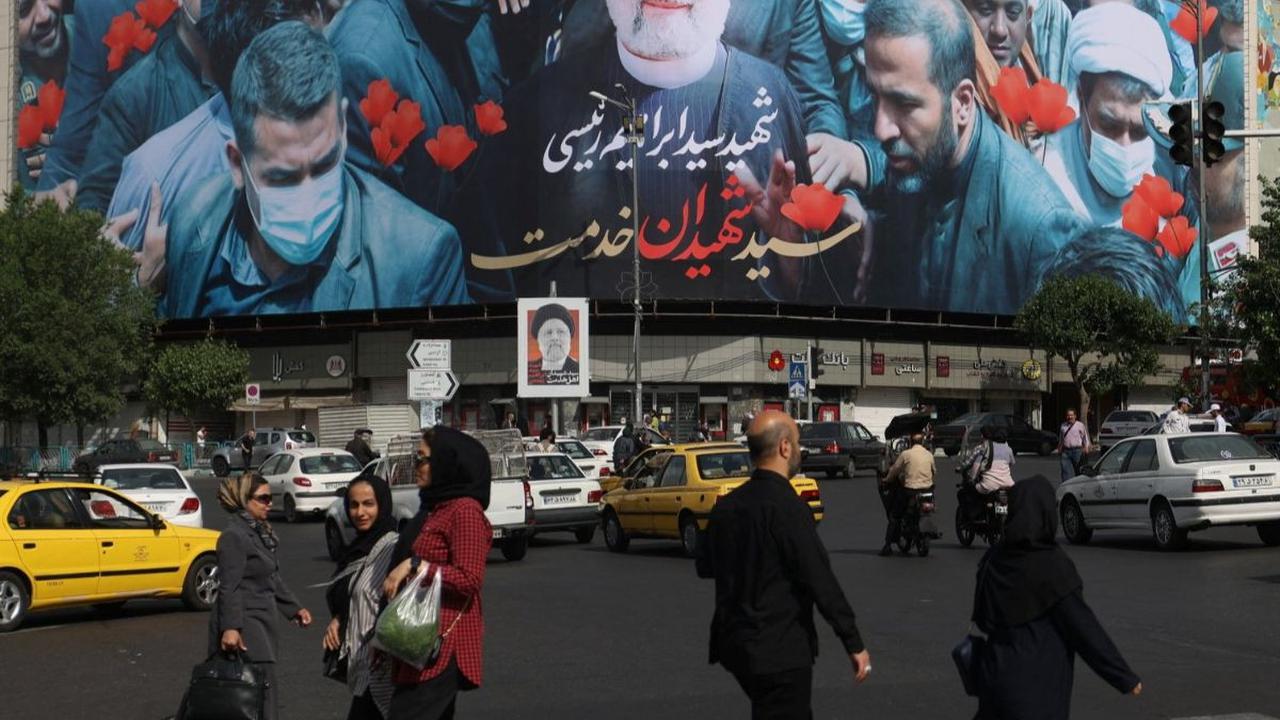 Sejumlah orang berjalan di depan baliho yang menampilkan almarhum Presiden Iran Ebrahim Raisi di Ibu Kota Teheran, Iran, Selasa (21/5/2024). Iran menetapkan masa berkabung selama lima hari untuk mengenang Presiden Ebrahim Raisi.&nbsp;Foto: Majid Asgaripou