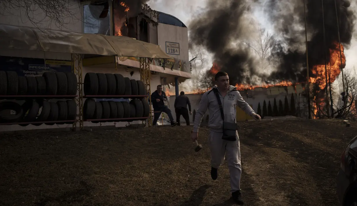 Orang-orang mencoba menyelamatkan barang-barang dari toko yang terbakar setelah serangan Rusia di Kharkiv, Ukraina, 25 Maret 2022. (AP Photo/Felipe Dana)
