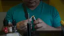 Seorang pelanggan mempersiapkan rokok elektrik di sebuah toko vape di Manila (20/11/2019). Presiden Filipina Rodrigo Duterte mengumumkan akan melarang penggunaan e-rokok dan memerintahkan polisi untuk menangkap orang-orang yang merokok e-rokok di depan umum. (AFP Photo/Dante Diosina Jr)