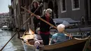 Elena Almansi (tengah), anggota Row Venice, mengajarkan mendayung gondola bagi wisatawan di sebuah kanal di Venesia, Italia pada 16 Mei 2019. Pengalaman ini bisa dimiliki dengan sekitar Rp 1,37 juta per gondola selama 90 menit untuk empat orang yang dimulai pukul 10.00 pagi. (MARCO BERTORELLO/AFP)