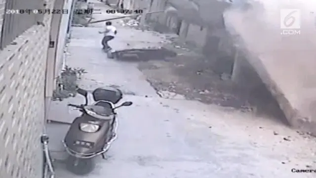 Seorang pengemudi skuter nyaris lolos terkubur oleh sebuah tembok yang runtuh di China selatan pada hari Selasa (22 Mei).