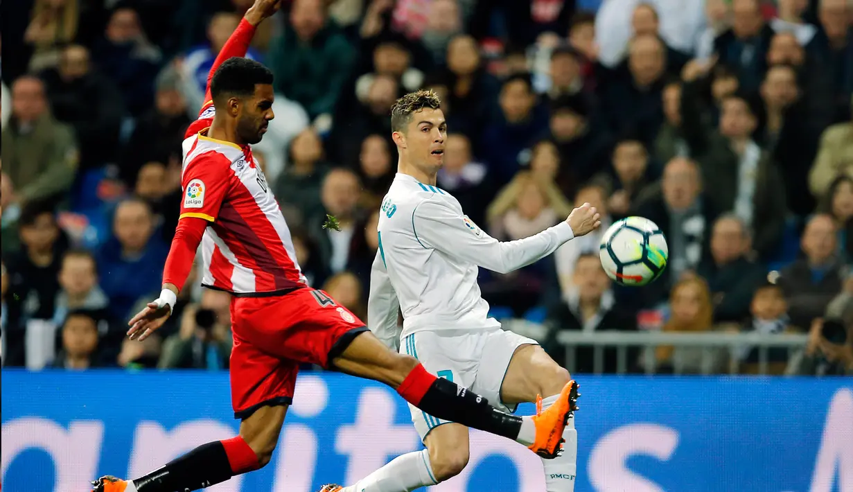 Striker Real Madrid Cristiano Ronaldo memberi umpan dan dihadang oleh pemain Girona Jonas Ramalho pertandingan La Liga Spanyol di stadion Santiago Bernabeu di Madrid (18/3). (AP Photo / Paul White)