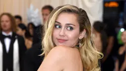 Penyanyi dan artis Hollywood, Miley Cyrus berpose setibanya pada ajang Met Gala 2018 di Metropolitan Museum of Art New York, Senin (7/5). Miley Cyrus tampil mengenakan gaun hitam yang memamerkan bagian punggung mulusnya. (Evan Agostini/Invision/AP)