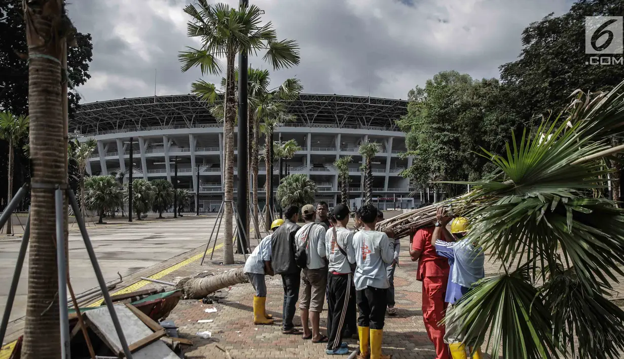Petugas menumbangkan pohon yang rusak akibat ulah oknum suporter yang menyaksikan laga Final Piala Presiden 2018 di Stadion Utama GBK, Jakarta, Minggu (18/2). Pemandangan tersebut tentu saja merusak keindahan area stadion. (Liputan6.com/Faizal Fanani)