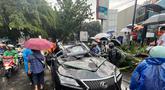 Sebuah mobil mewah bermerek Lexus tertimpa pohon tumbang di Jalan Metro Pondok Indah, Jakarta, Minggu (26/10/2025). (merdeka.com/Arie Basuki)