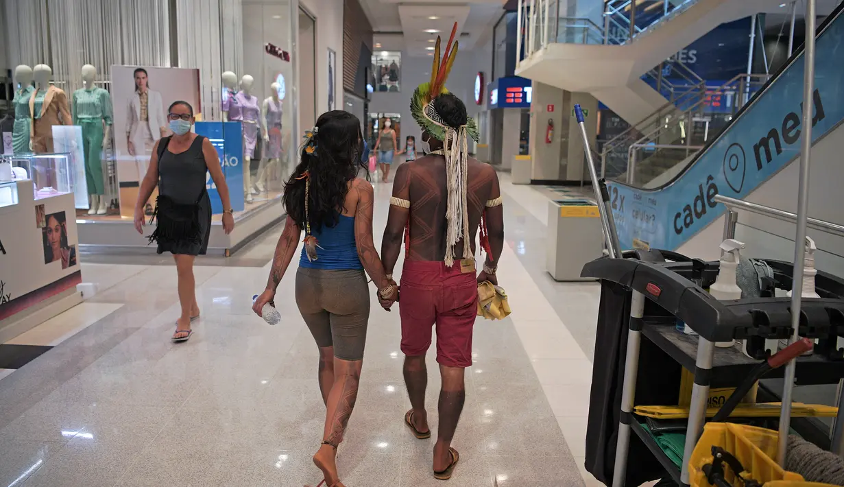 Sepasang suku Kariri berjalan di mal di Brasilia, Brasil (26/8/2021).  Ia masuk ke dalam mal saat para pengunjuk rasa suku pribumi lainnya berkumpul di ibu kota Brasil saat Mahkamah Agung bersiap untuk menangani kasus yang dapat menghilangkan keberatan di tanah leluhur mereka. (AFP/Carl De Souza)