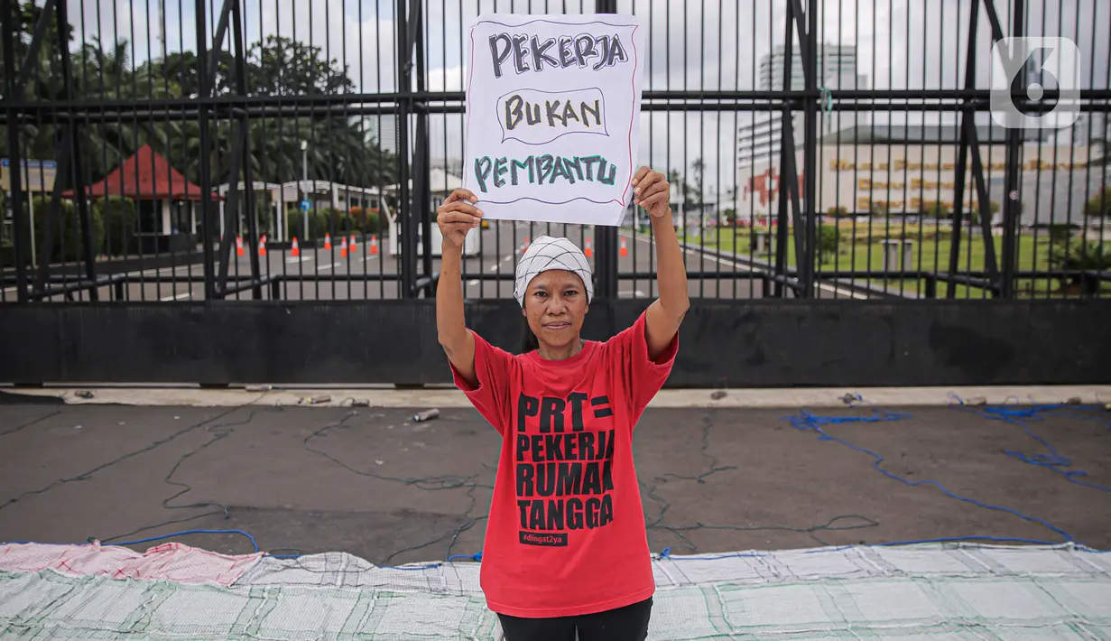 Salah satu peserta aksi yang tergabung dalam Koalisi Sipil Untuk UU Perlindungan PRT mengangkat poster di depan Gedung DPR, Jakarta, Rabu (15/7/2023). Dalam aksinya, pendemo yang sebagian besar ibu-ibu ini juga membawa spanduk dan poster berisi tuntutan mereka. (Liputan6.com/Faizal Fanani)