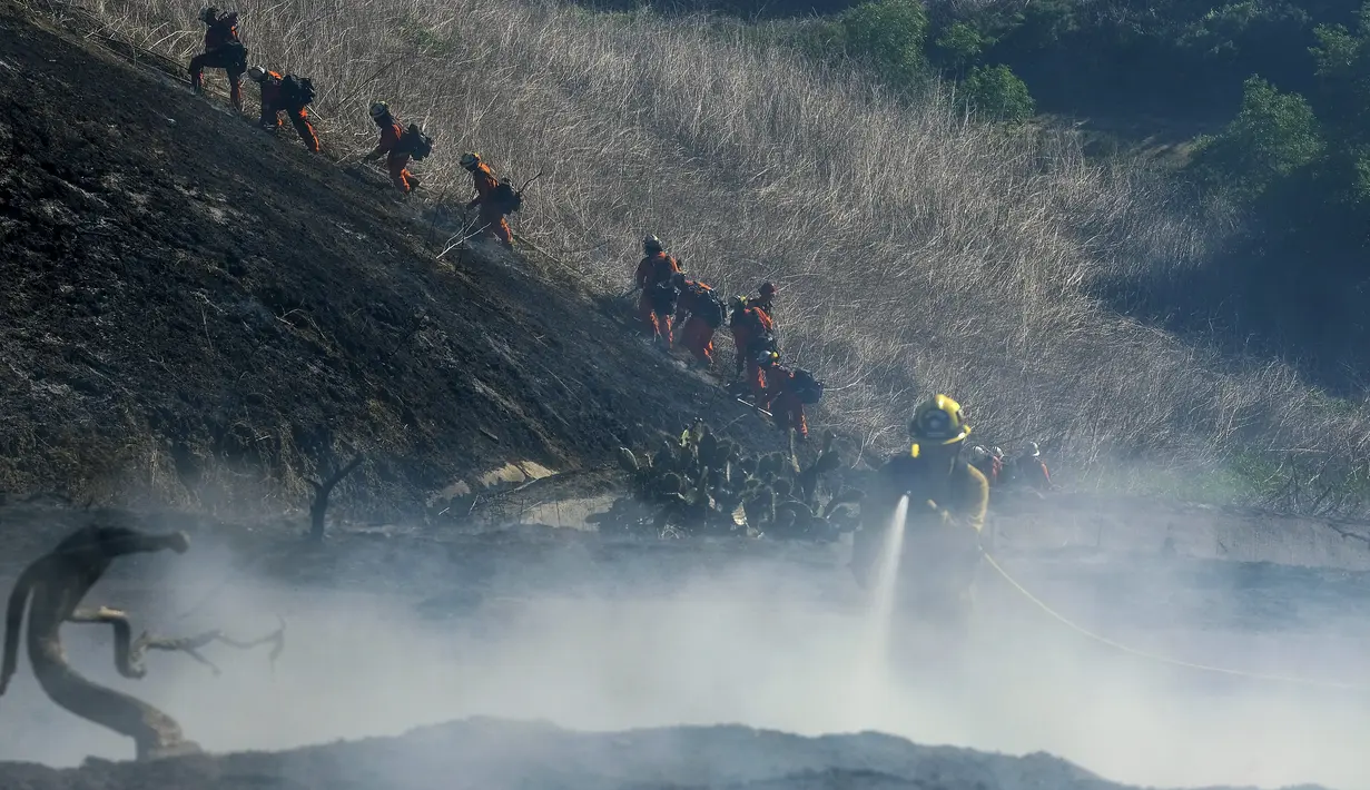 Petugas pemadam kebakaran bekerja pada kebakaran hutan di dekat rumah di Whittier, California (10/2/2022). Kebakaran hutan yang dipicu oleh angin kencang Santa Ana meletus di perbukitan di pantai California Selatan Kamis pagi. (AP Photo/Ringo H.W. Chiu)