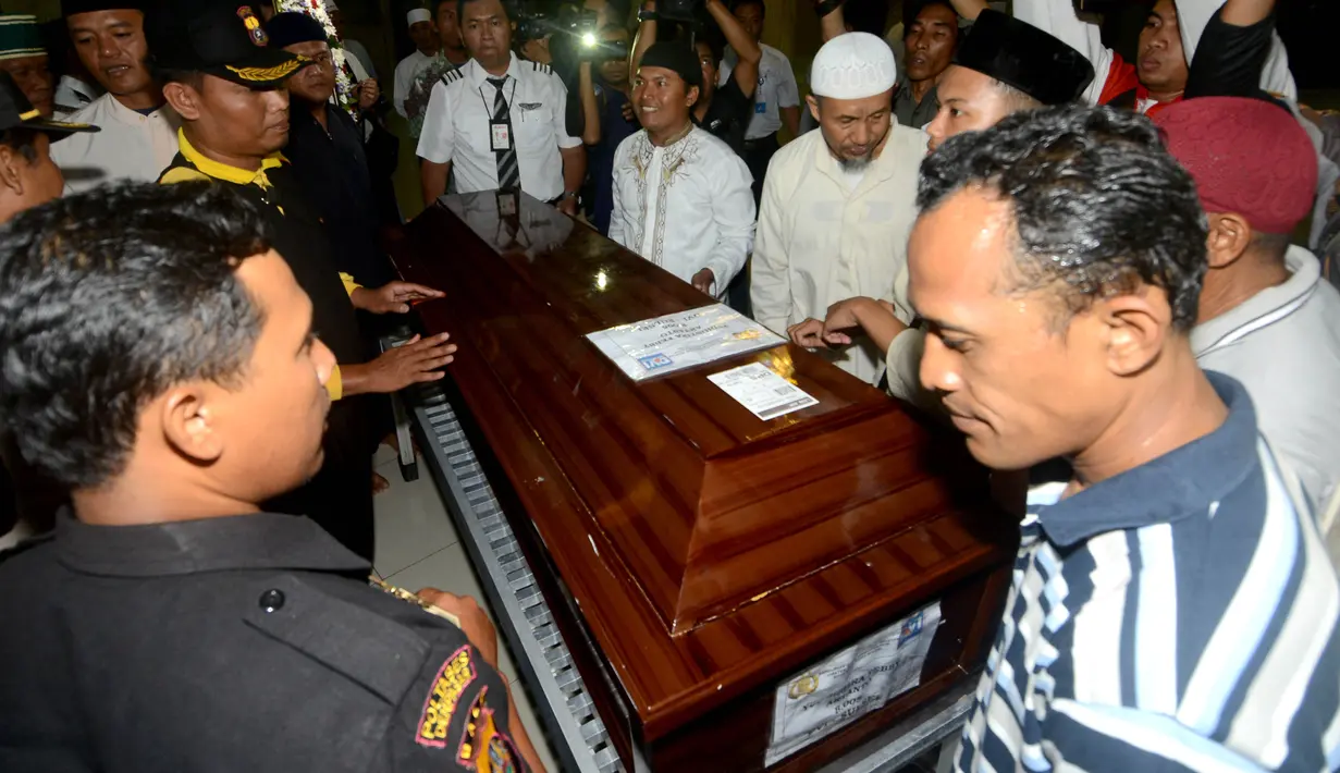 Keluarga berdiri di dekat peti jenazah Yudhistira Febbi Arianto, co pilot pesawat Aviastar yang tiba di sebuah masjid dekat Bandara Ngurah rai, Bali, Kamis (8/10). Pesawat Aviastar jatuh dan menewaskan 3 kru dan 7 penumpang. (AFP PHOTO/SONNY TUMBELAKA)