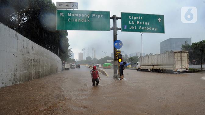 Seorang pria menyusuri banjir yang menggenangi Jalan Tol JORR di kawasan TB Simatupang, Jakarta Selatan, Sabtu (20/2/2021). Banjir terjadi akibat luapan Kali Serua yang berada di pinggir jalan tol. (merdeka.com/Arie Basuki)