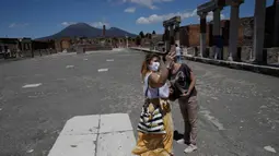Dua perempuan berswafoto saat mengunjungi situs arkeologi Pompeii usai kebijakan lockdown selama dua bulan untuk mengendalikan penyebaran Covid-19 di Italia, Selasa (26/5/2020). Salah satu situs arkeologi paling terkenal di dunia ini dibuka kembali untuk umum pada 26 Mei. (AP/Alessandra Tarantino)