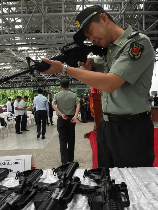 Seorang anggota Tentara Pembebasan Rakyat China mencoba senapan CQ-A5b (M4) yang disumbangkan oleh pemerintah China ke Filipina di Manila, Filipina (5/10). Otoritas China menghadiahkan 3 ribu pucuk senapan serbu untuk Filipina. (AFP Photo/Ted Aljibe)