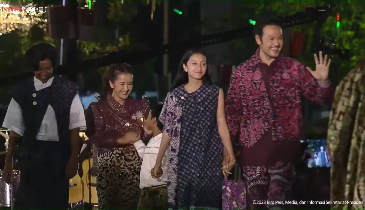 The Sasono Family; yaitu keluarga Dwi Sasono dan Widi Mulia pun tampil kompak di runway Istana Berbatik. Widuri tampil cantik dengan midi dress batik tanpa lengan berwarna biru, ia menyematkan kain batik serasi di sebelah bahunya. Sedangkan Dru Prawiro mengenakan atasan putih polos yang ditumpuk dengan outer batik biru yang serasi dan berpotongan asimetris, pas dengan bawahan yang dijadikan sebagai rok. Sedangkan anak terkecilnya Den Bagus Satrio tampil menggemaskan dengan atasan lengan panjang putih polos dipadu dengan kain batik cokelat sebagai bawahan. [Foto: YouTube/Sekretariat Presiden]