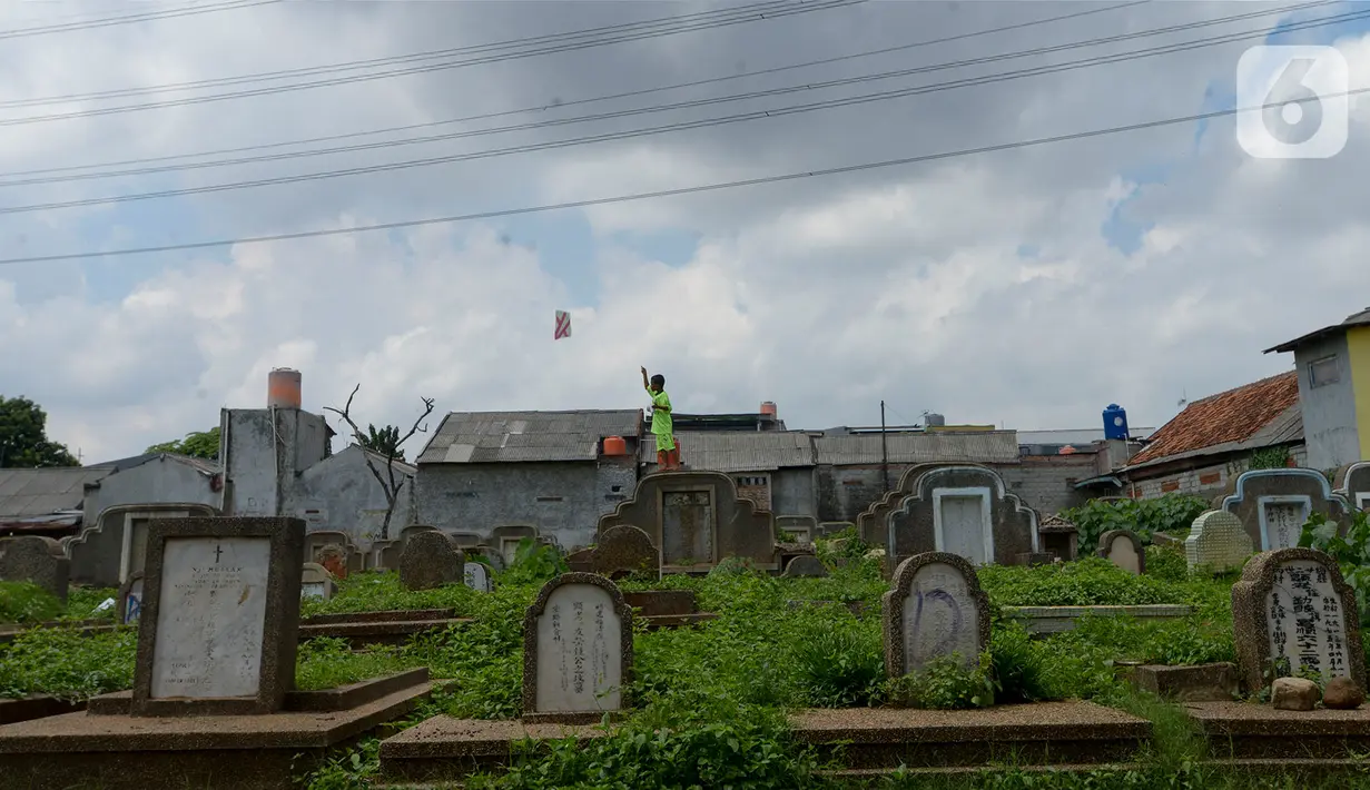 Anak-anak menerbangkan layang-layang di Tanah Makam Cipinang Besar Utara, Jakarta, Selasa (14/1/2020). Pemprov DKI Jakarta berencana terus menambah Ruang Publik Terpadu Ramah Anak (RPTRA) di sejumlah wilayah. (merdeka.com/Imam Buhori)