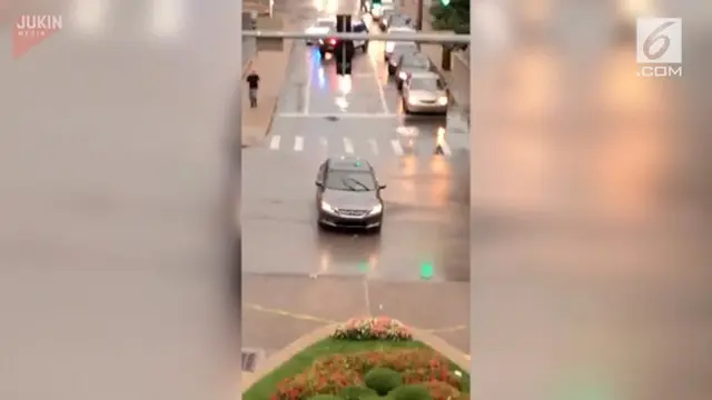 Seorang pengemudi tertidur di dalam mobilnya saat berhenti di persimpangan lampu merah. Polisi mencoba membangunkannya dengan memecahkan kaca mobil.