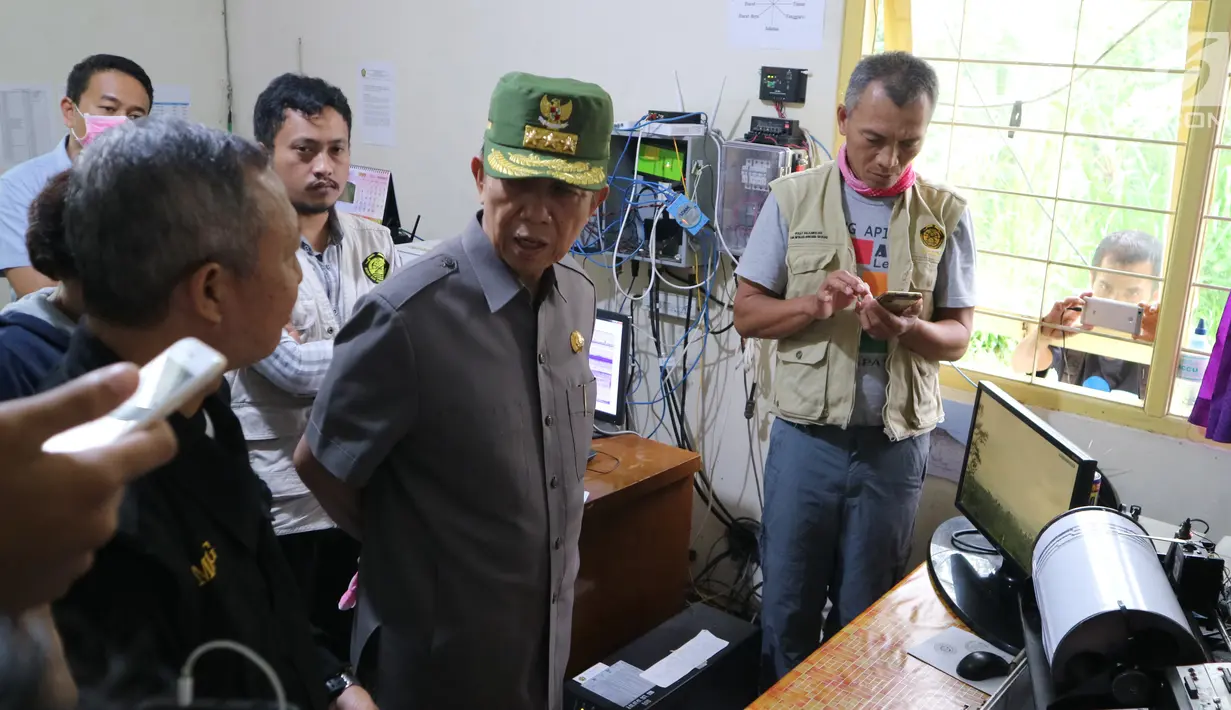 Gubernur Bali Made Mangku Pastika mendengarkan penjelasan di Pos Pengamatan Gunung Api Agung, Kabupaten Karangasem, Senin (27/11). Gubernur Bali memastikan pemerintah akan membantu mereka yang terdampak letusan Gunung Agung. (Liputan6.com/Andi Jatmiko)