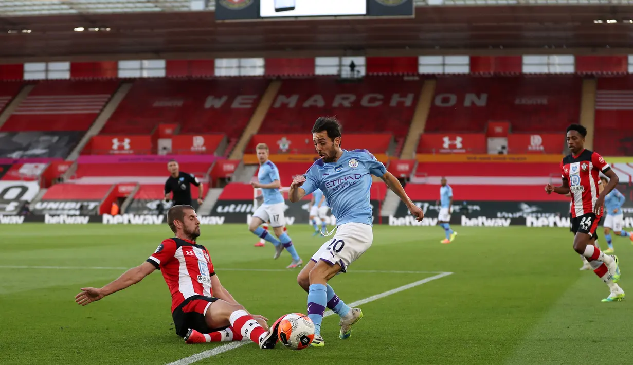Gelandang Manchester City, Bernardo Silva (tengah) berebut bola dengan bek Southampton Jack Stephens dalam lanjutan Liga Inggris di St. Mary Stadium, Minggu (5/7/2020).  Manchester City gagal memetik poin penuh setelah kalah tipis 0-1 saat bertandang ke markas Southamtpon. (Catherine Ivill/POOL/AFP)