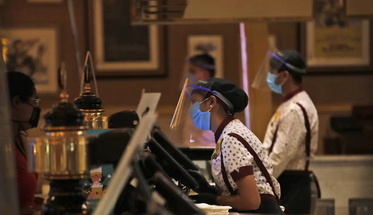 Karyawan bioskop PVR yang mengenakan pelindung wajah dan topeng berdiri di konter makanan saat bioskop dibuka kembali di New Delhi, India (15/101/2020). (AP Photo/Manish Swarup)