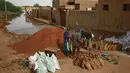 Pria Sudan mengisi karung pasir untuk membuat penghalang banjir di sekitar rumah mereka di area alqamayir di kota kembar ibu kota Omdurman (26/8/2020). (AFP Photo/Ashraf Shazly)