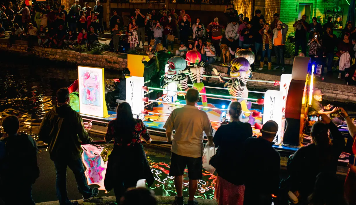 Warga melihat kendaraan hias melintas selama parade Hari Sungai Mati di San Antonio, Texas, Amerika Serikat, 29 Oktober 2021. Warga berkumpul untuk merayakan, memperingati, dan mengenang orang-orang terkasih yang telah meninggal untuk Día de los Muertos tahun ini. (Brandon Bell/Getty Images/AFP)