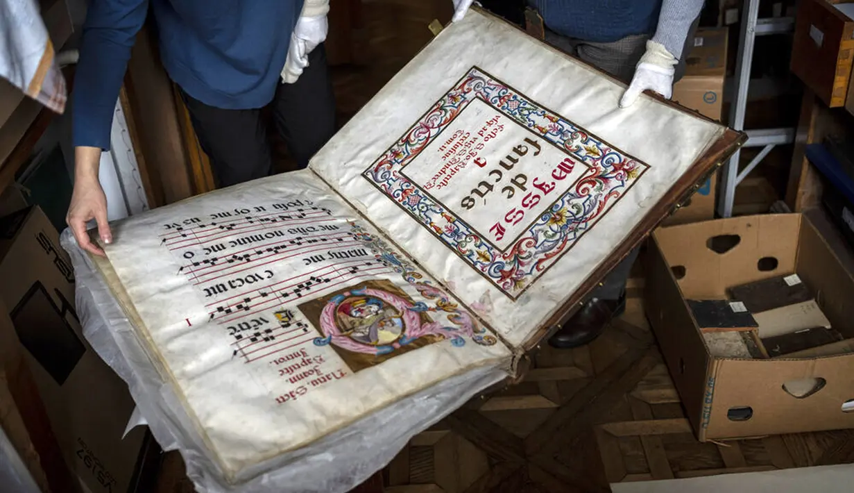 Para pekerja bagian manuskrip langka dan buku cetak tua di Museum Nasional Andrey Sheptytsky menyimpannya dalam kotak kardus untuk mengurangi risiko kerusakan jika terjadi serangan Rusia di Kota Lviv, Ukraina, 4 Maret 2022. (AP Photo/Bernat Armangue)