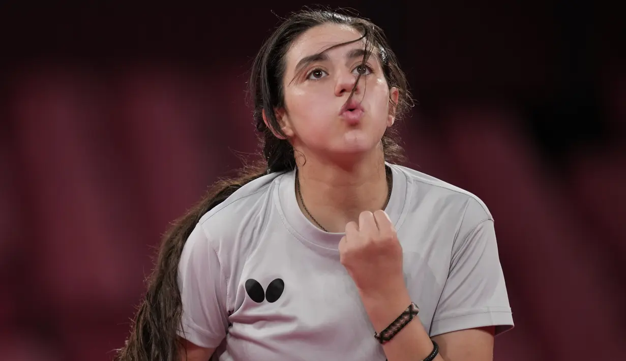 Ekspresi petenis meja Suriah Hend Zaza saat melawan Liu Jia dari Austria selama pertandingan babak penyisihan tunggal tenis meja putri di Olimpiade 2020 di Tokyo, Sabtu (24/7/2021). Di negara asalnya,  bocah kelahiran 2009 itu adalah juara nasiona. (AP Photo/Kin Cheung)