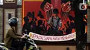 Pengendara melintas di depan mural berisi kritik terhadap kinerja polisi di Lapangan Bhayangkara Mabes Polri, Jakarta, Minggu (31/10/2021). Lomba mural 2021 Piala Kapolri menampilkan sejumlah karya berisi kritik terhadap polisi yang dituangkan pada media triplek. (Liputan6.com/Helmi Fithriansyah)