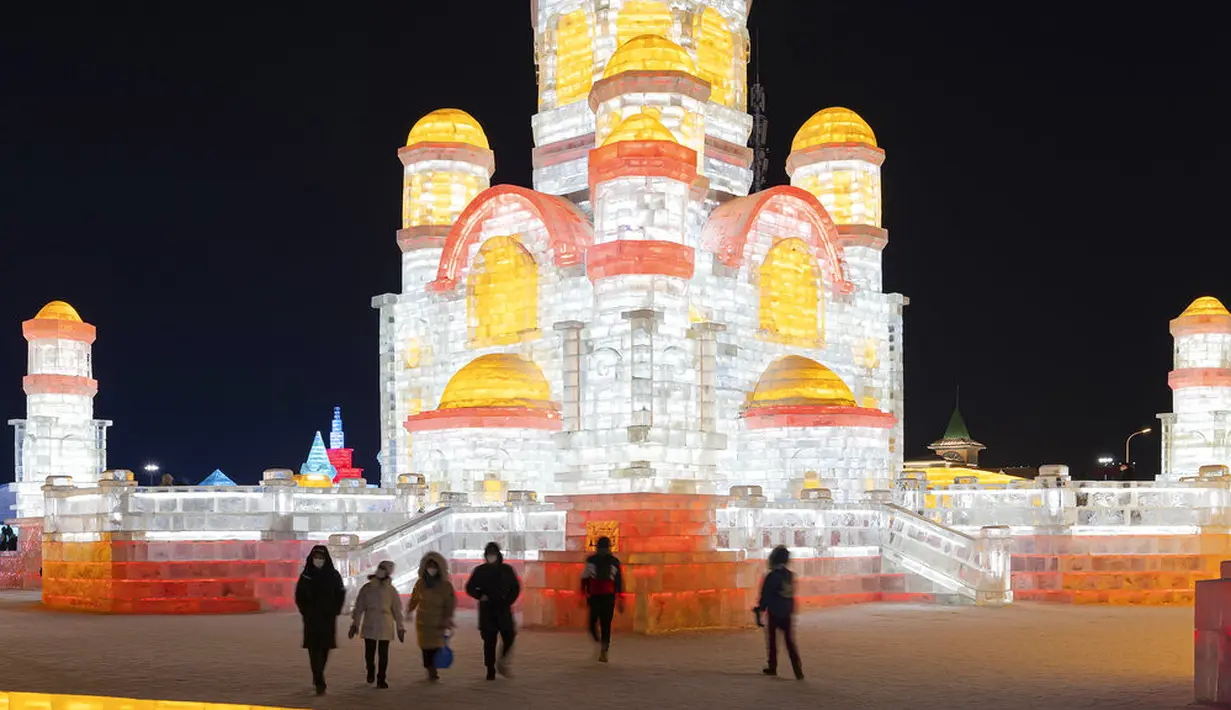 Pengunjung mengamati pahatan es yang dihiasi sorotan lampu warna-warni di Festival Dunia Es dan Salju Harbin, Harbin, Provinsi Heilongjiang, China, Selasa (5/1/2021). Festival ini melingkupi banyak instalasi dan aktivitas yang berhubungan dengan salju. (Chinatopix via AP)