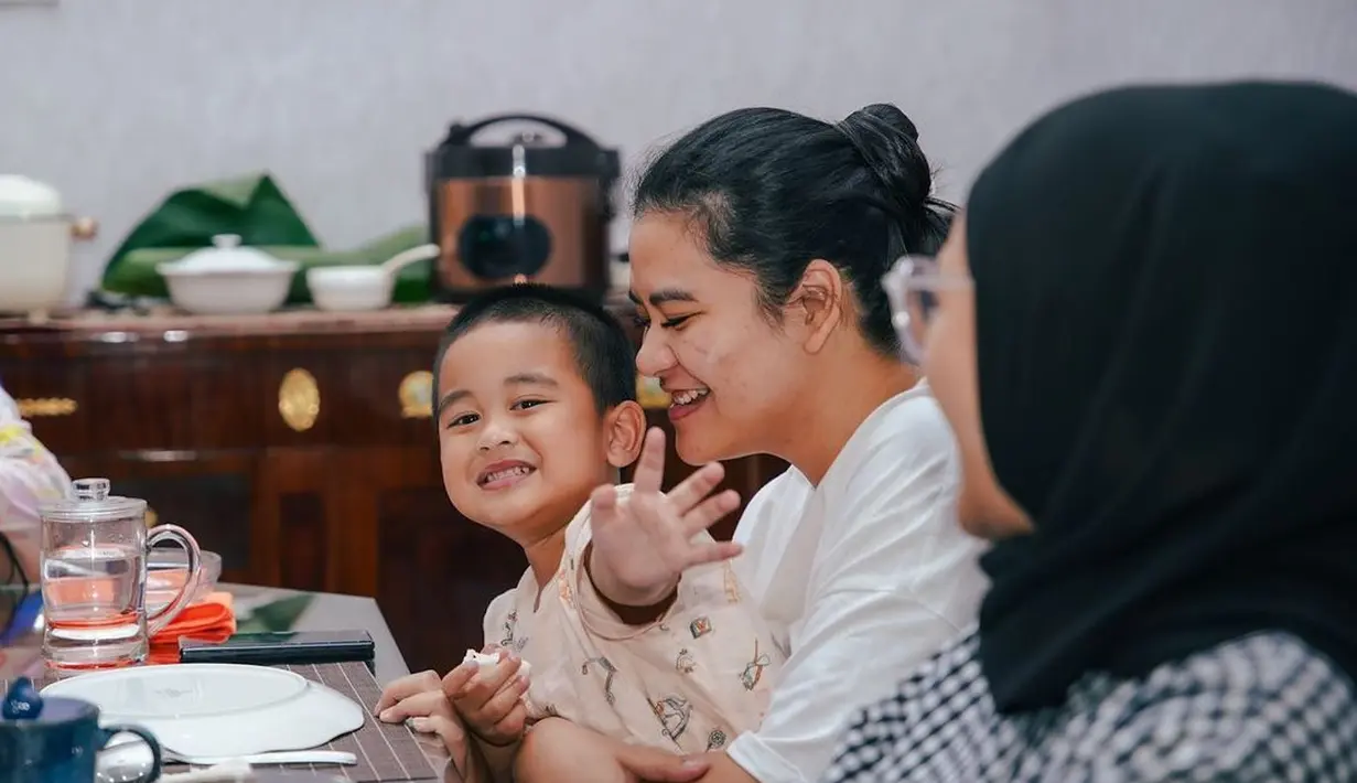 Potret hangat Kahiyang Ayu saat sedang bersama keluarganya. Ia memangku anak laki-lakinya dengan tampilan sederhana, kaus putih dan wajah yang dirias minimalis, rambut digulung ke atas dengan gaya yang rapi. [Foto: Instagram/bobbynst]