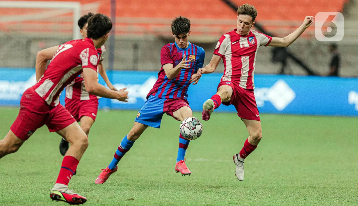 Pemain Barcelona U-18 (tengah) menggiring bola melewati para pemain Altetico Madrid U-18 pada pertandingan International Youth Championship (IYC) 2021 di Jakarta International Stadium (JIS), Jakarta, Selasa (19/4/2022). Barcelona U-18 menang 1-0. (Liputan6.com/Faizal Fanani)