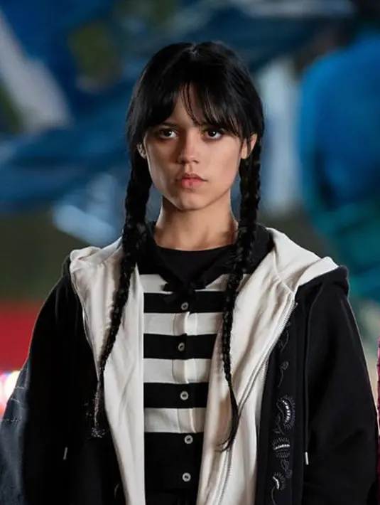 Jenna mengenakan dua lapis hoodie berwarna hitam dan putih dengan kaos strip berwarna senada. Penampilan karakter Wednesday membuat aktris muda tersebut selalu tampil dengan gaya pakaian bertema gothic. (Instagram/@diet_prada/@netflix)